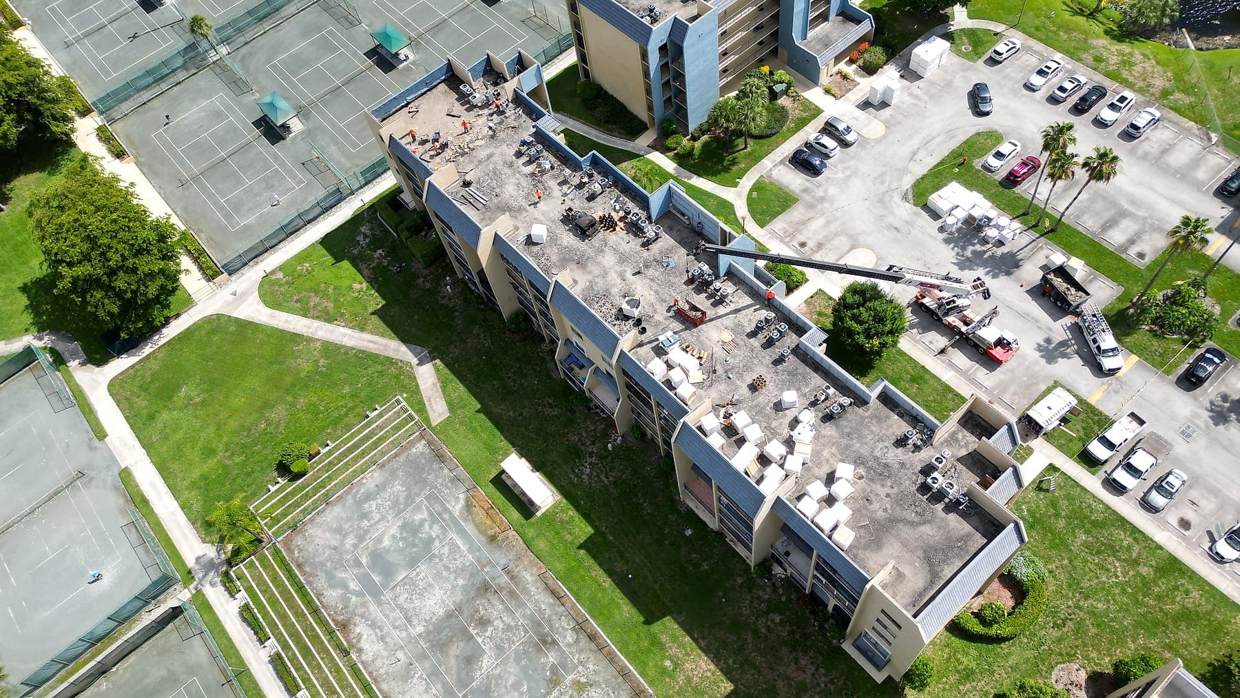 Aerial view of a garden-style condominium campus with courts and mature landscaping