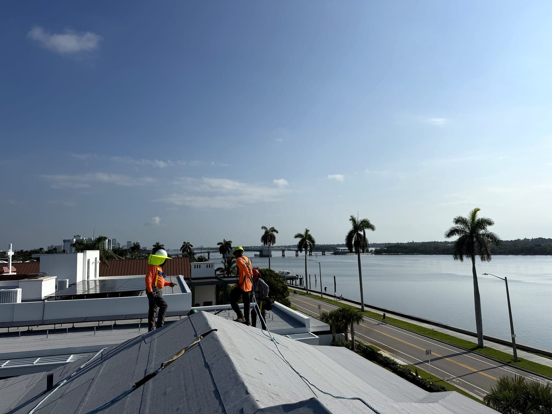 Beachfront crew members in high-visibility gear on a rooftop overlooking the Intracoastal Waterway
