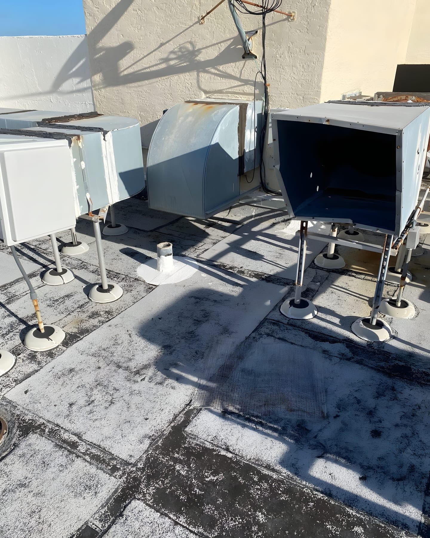 An aged built-up roof with weathered ductwork and equipment supports awaiting repair