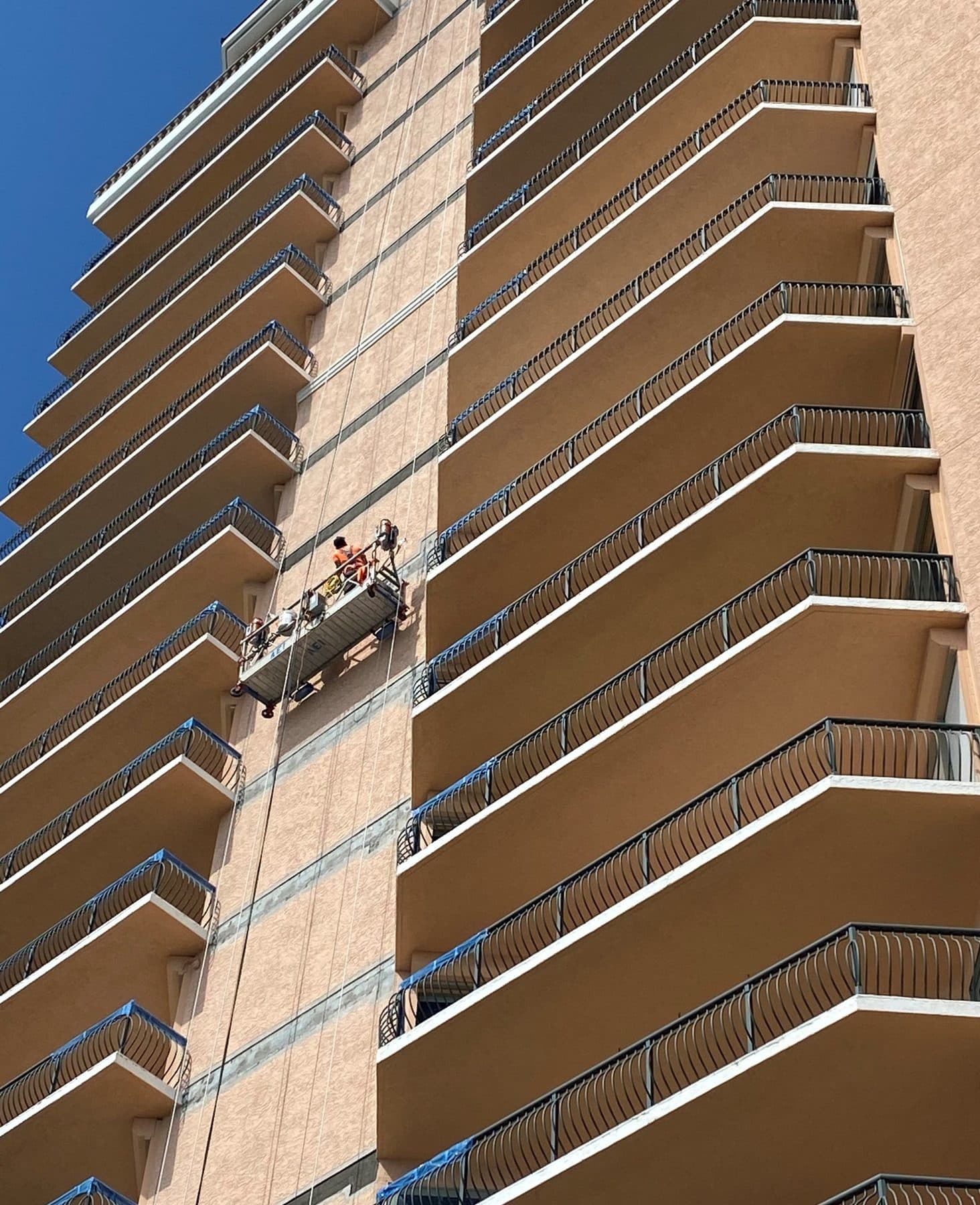 Crew repainting the exterior of a high-rise condominium from a suspended swing stage