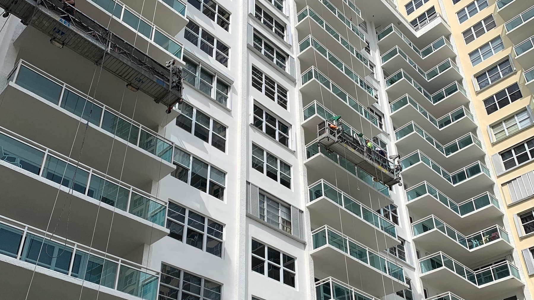 Two suspended swing stages with crews working across a high-rise tower face