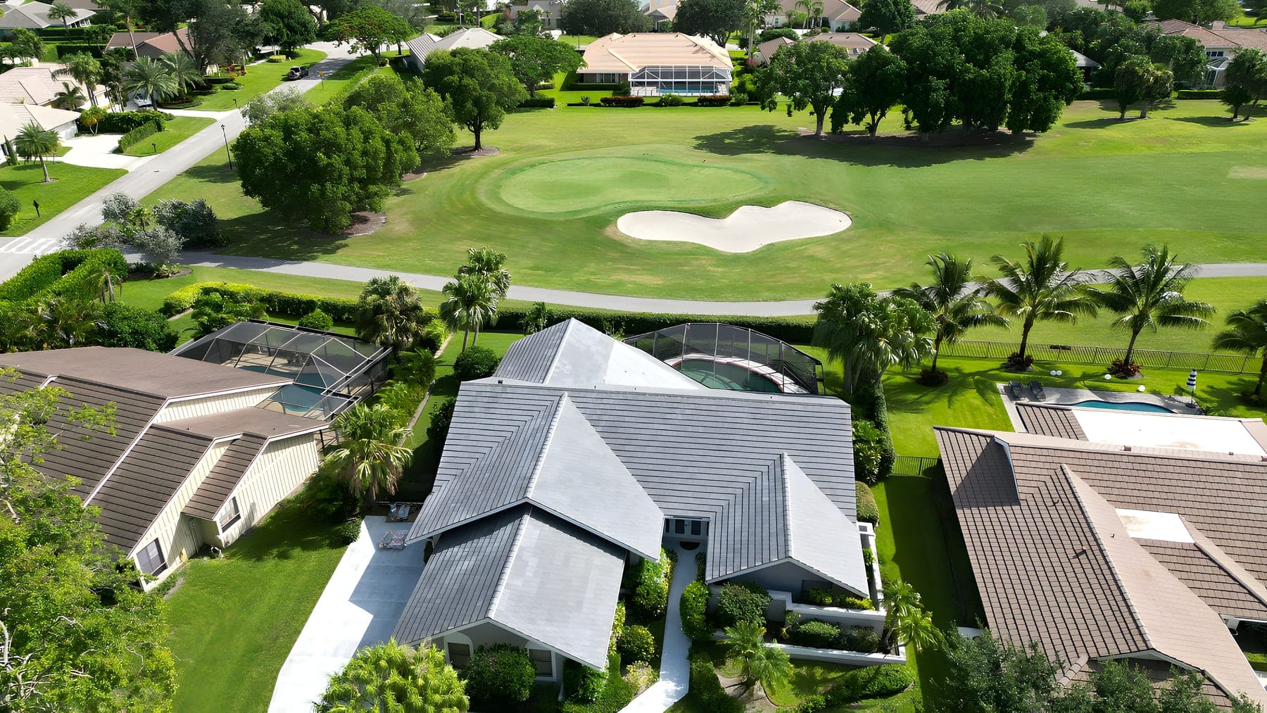 Aerial view of a single-family home and pool backing onto a golf course fairway