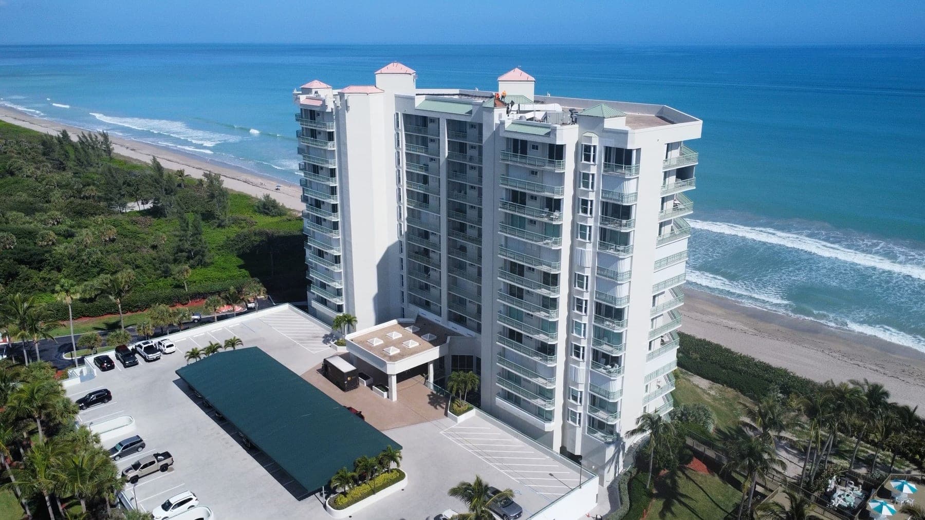 Aerial view of an oceanfront condominium tower with crew members visible on the rooftop