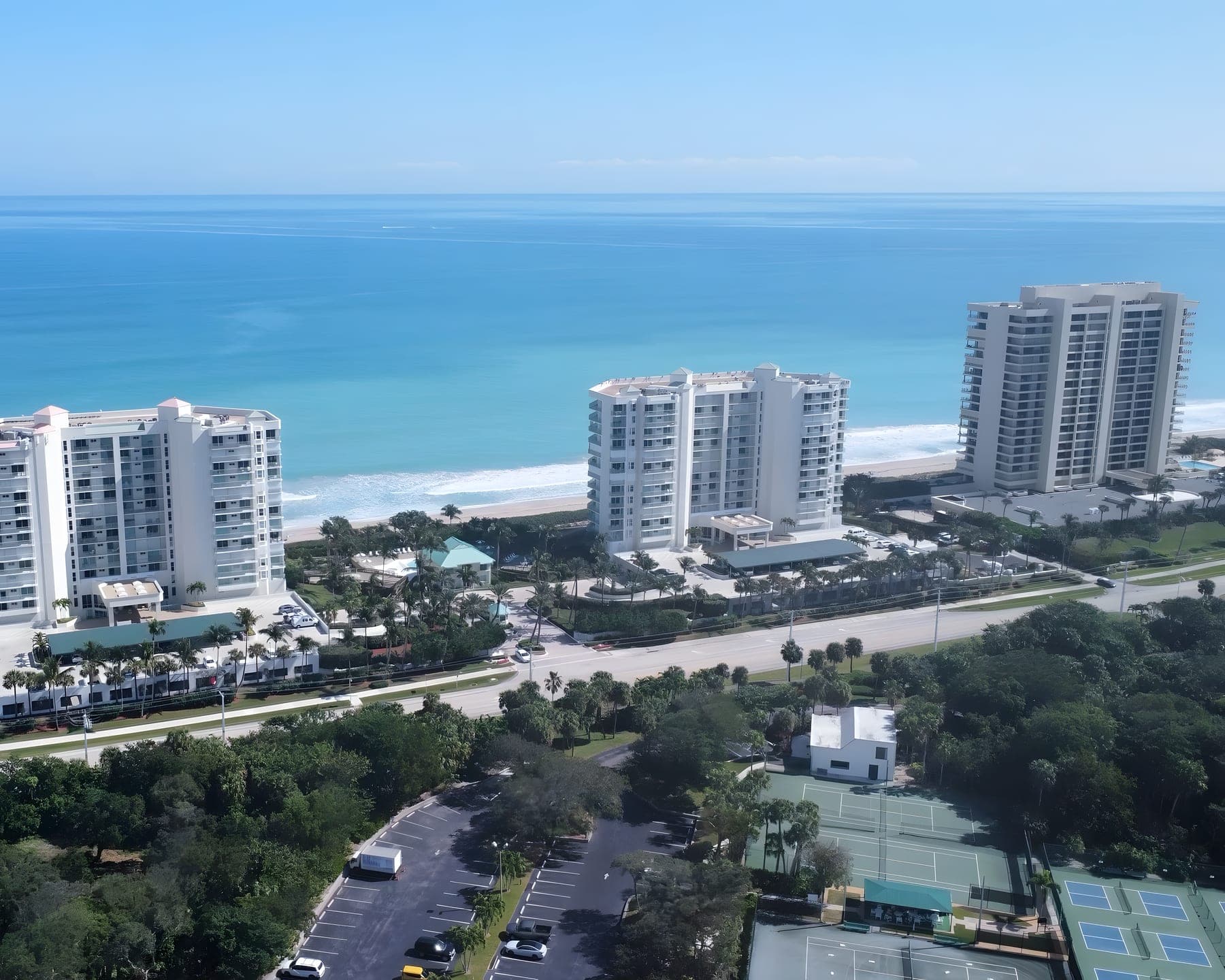 Aerial view of oceanfront condominium towers along a turquoise Florida shoreline
