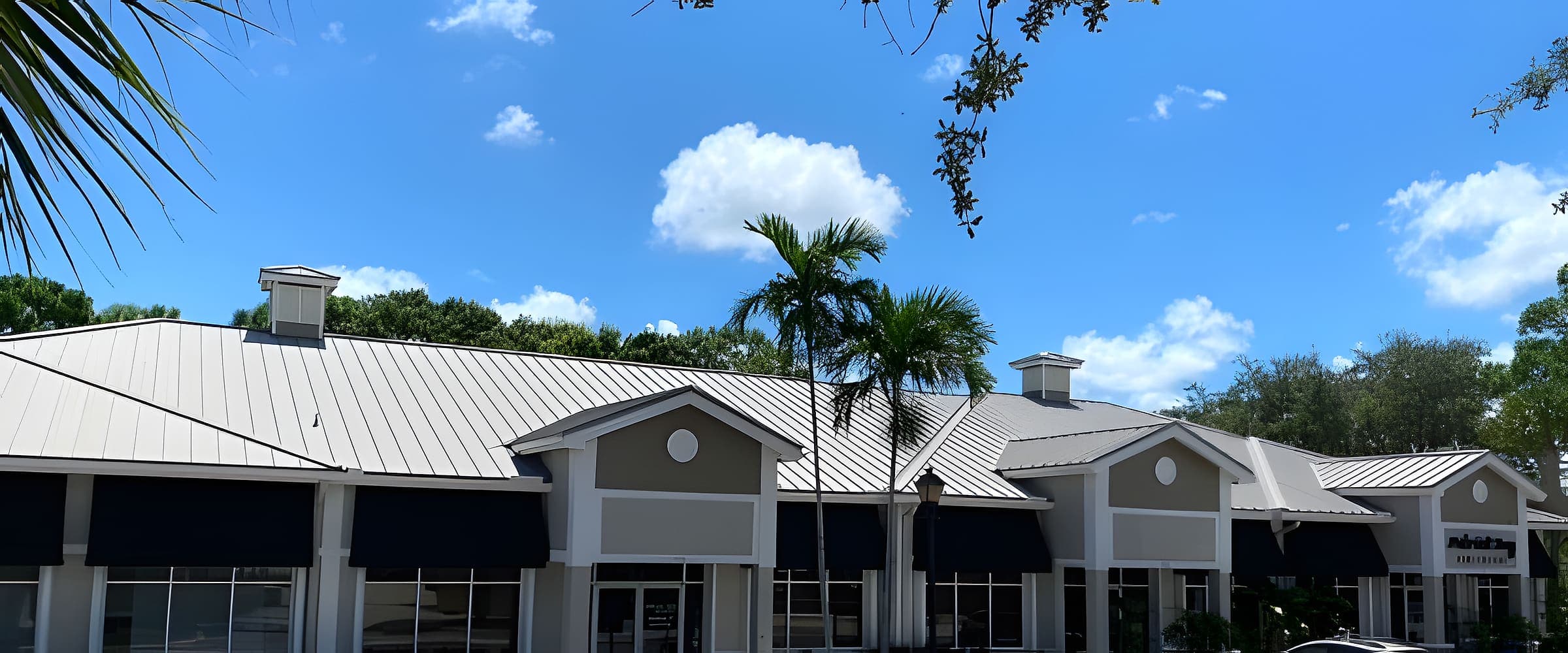 Storefronts of a Jupiter retail plaza with palms under a blue sky