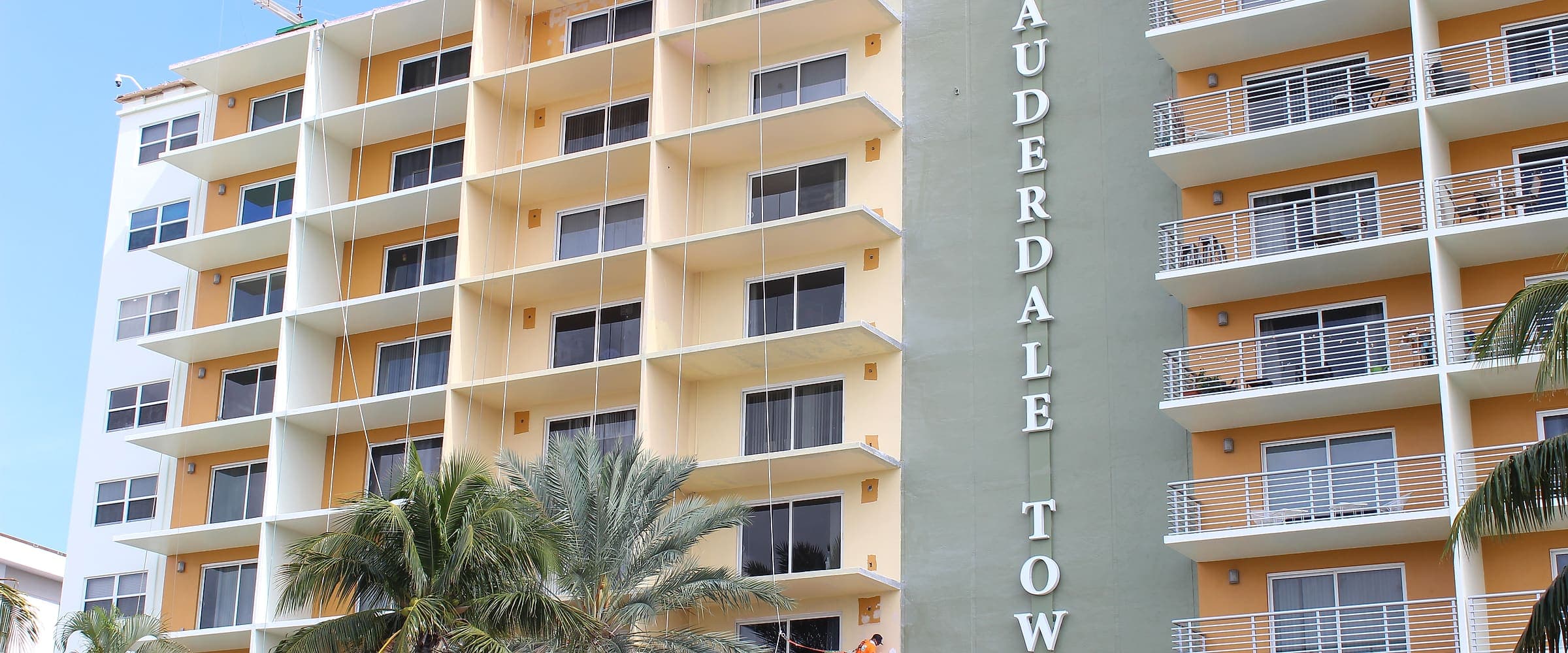 Crew members working from a swing stage on a mid-rise condominium exterior