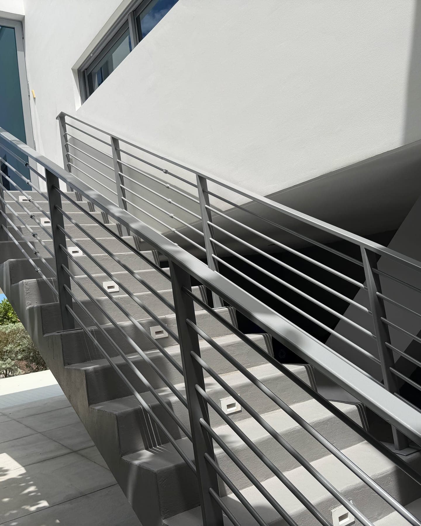 Freshly coated exterior stair treads and landing with metal railings on a modern building